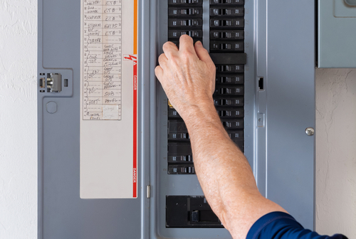 Resetting,tripped,breaker,in,residential,electricity,power,panel.,male,electrician